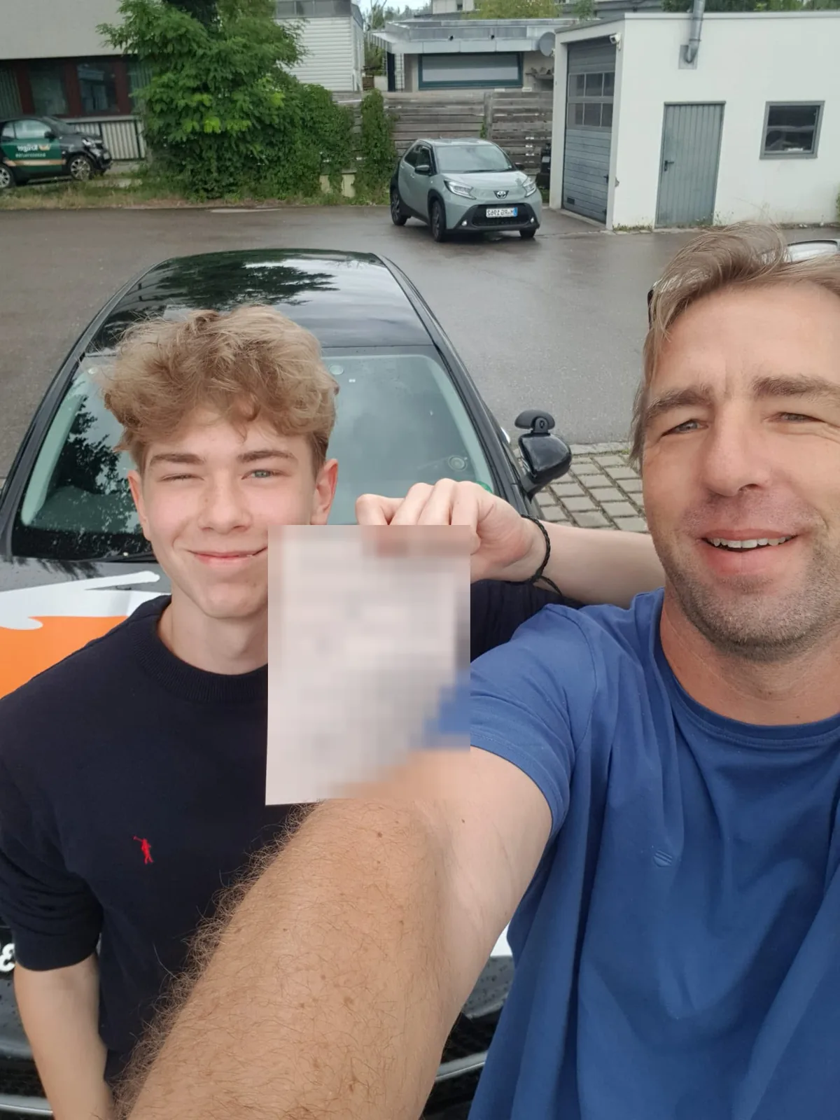 Junger Fahrschüler zeigt seine Bescheinigung, daneben sein Fahrlehrer
