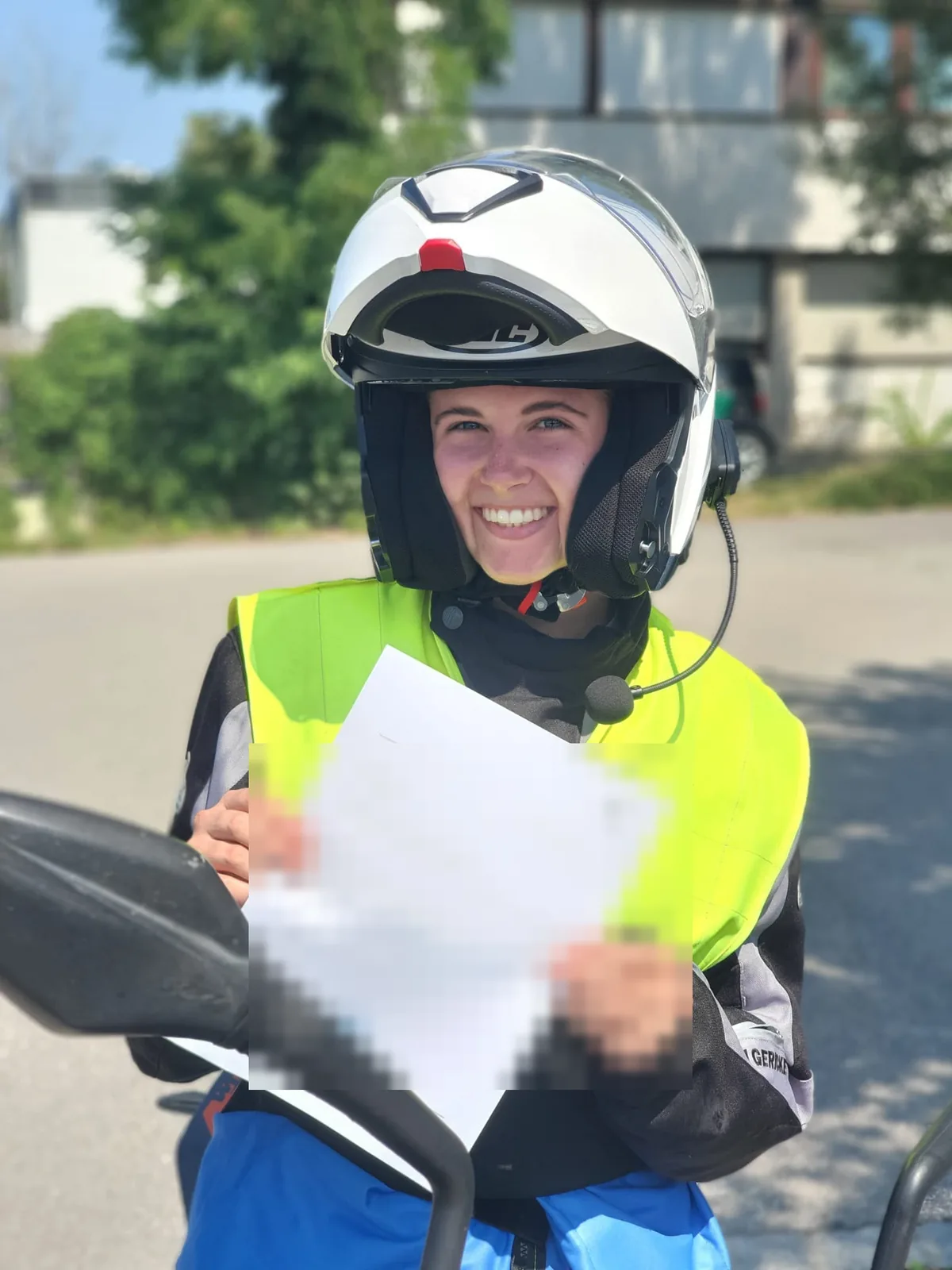 Motorradschülerin mit Helm und Bescheinigung nach der bestandenen Prüfung