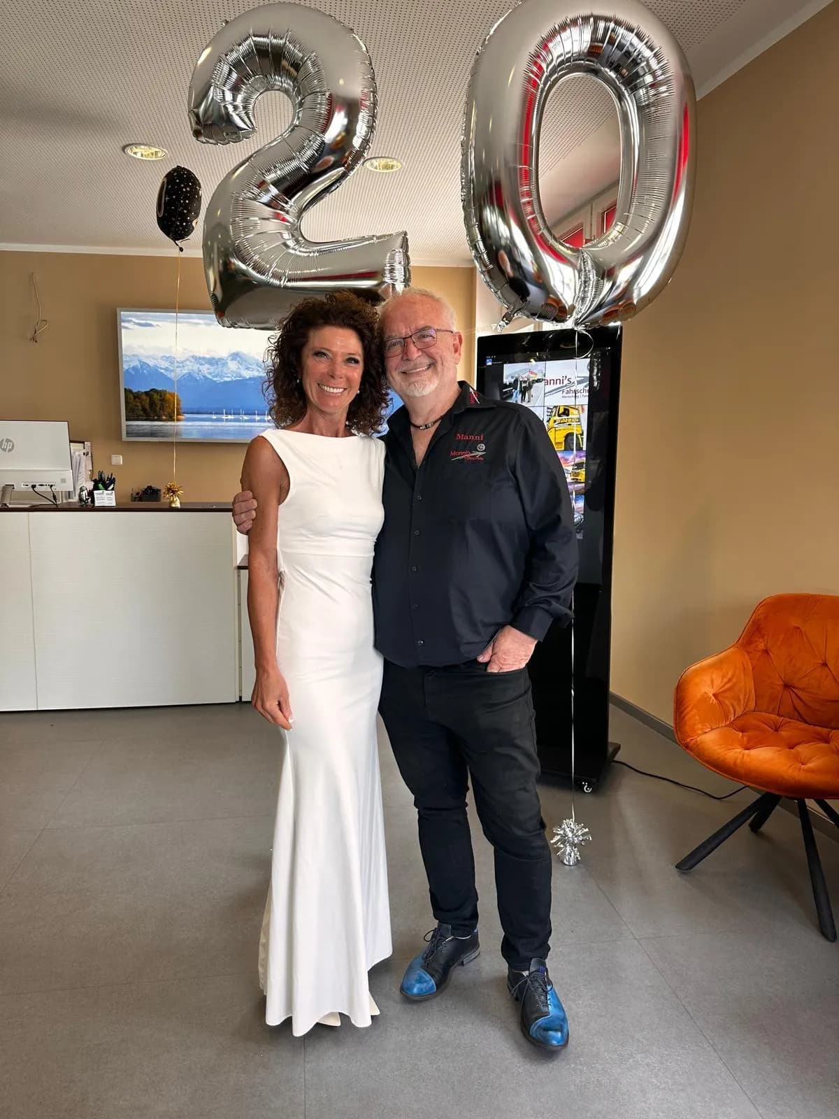 Manni mit Kollegin unter den silbernen 20er-Ballons bei der Jubiläumsfeier
